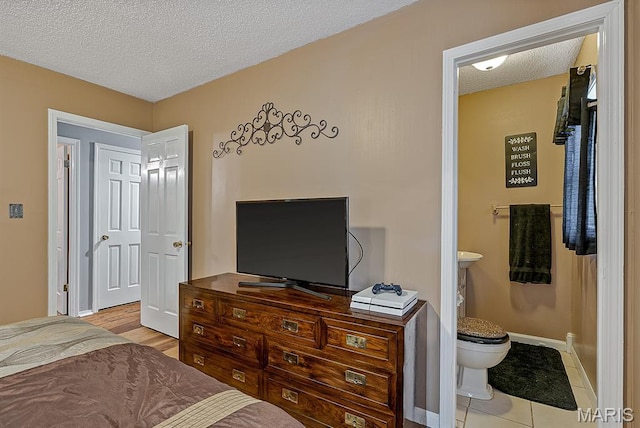 17504 Division St, Kennett, MO 63857 - bedroom with a textured ceiling, baseboards, ensuite bathroom, and light tile patterned flooring