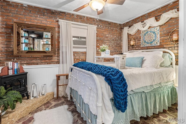 698N 3rd St, Saint Genevieve, MO 63670 - bedroom with a wood stove, brick wall, wainscoting, a ceiling fan, and crown molding