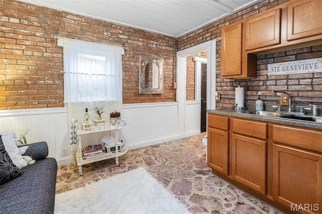 698N 3rd St, Saint Genevieve, MO 63670 - kitchen with brick wall, a wainscoted wall, brown cabinetry, and dark countertops