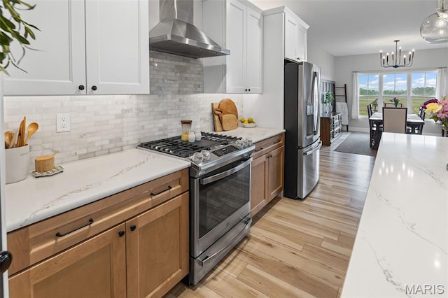 8353 Maple Grove Rd, Troy, IL 62294 - kitchen with stainless steel appliances, wall chimney range hood, a chandelier, light wood-style flooring, and light stone countertops