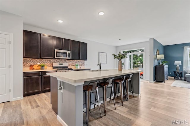 803 Brimley Dr, Cottleville, MO 63304 - kitchen with stainless steel appliances, light countertops, a kitchen breakfast bar, dark brown cabinetry, and a kitchen island with sink