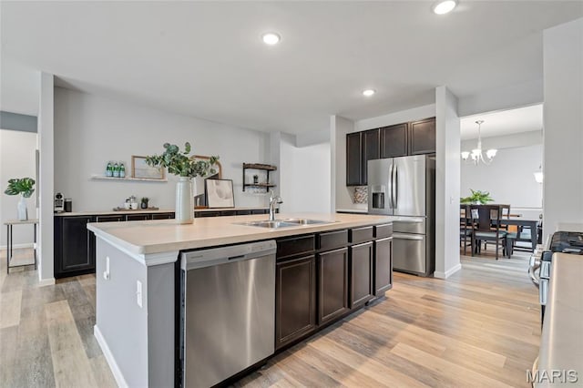 803 Brimley Dr, Cottleville, MO 63304 - kitchen featuring appliances with stainless steel finishes, light wood finished floors, light countertops, dark brown cabinetry, and a kitchen island with sink
