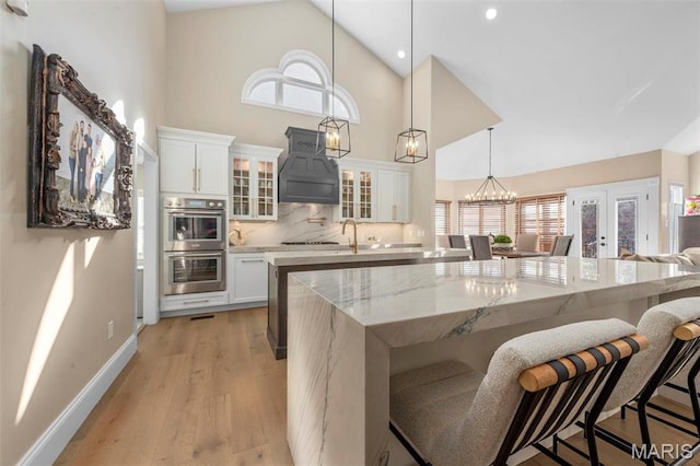 1315 Wildhorse Meadows Dr, Chesterfield, MO 63005 - kitchen featuring high vaulted ceiling, a kitchen island, custom exhaust hood, a breakfast bar, and light wood-type flooring