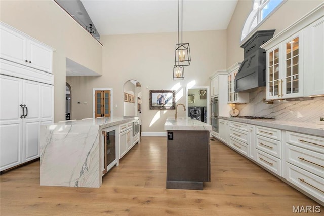 1315 Wildhorse Meadows Dr, Chesterfield, MO 63005 - kitchen with a center island with sink, arched walkways, a high ceiling, stainless steel appliances, and white cabinetry