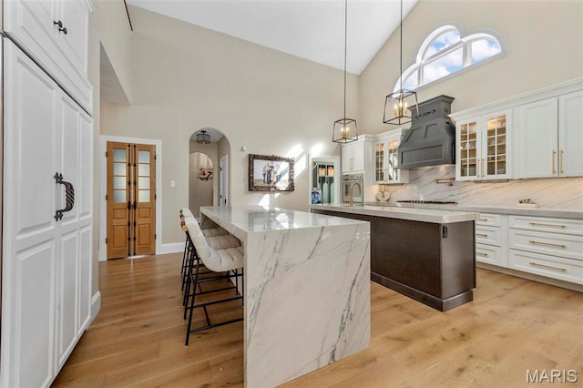 1315 Wildhorse Meadows Dr, Chesterfield, MO 63005 - kitchen with a center island, high vaulted ceiling, arched walkways, decorative backsplash, and white stovetop