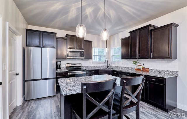 1810 Barclay Bluff Ct, Wentzville, MO 63385 - kitchen featuring stainless steel appliances, tasteful backsplash, dark brown cabinets, light stone counters, and wood finished floors