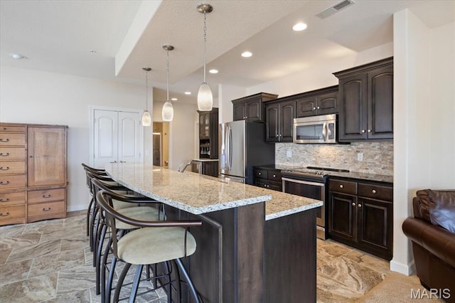 18051 Blue Anchor Dr Unit 533, Gravois Mills, MO 65037 - kitchen with appliances with stainless steel finishes, a breakfast bar, a kitchen island, backsplash, and light stone counters