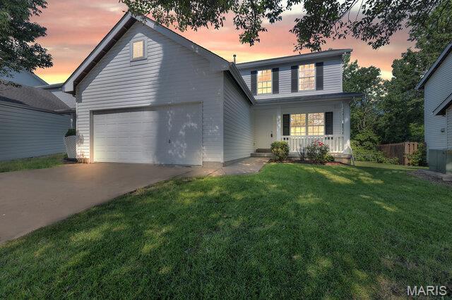 1305 Flintshire Ln, Lake St Louis, MO 63367 - traditional-style house featuring covered porch, a garage, driveway, and a lawn