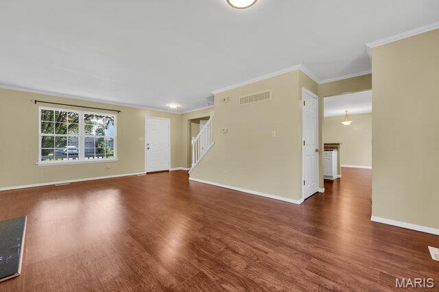 1305 Flintshire Ln, Lake St Louis, MO 63367 - unfurnished living room with crown molding, wood finished floors, and stairway