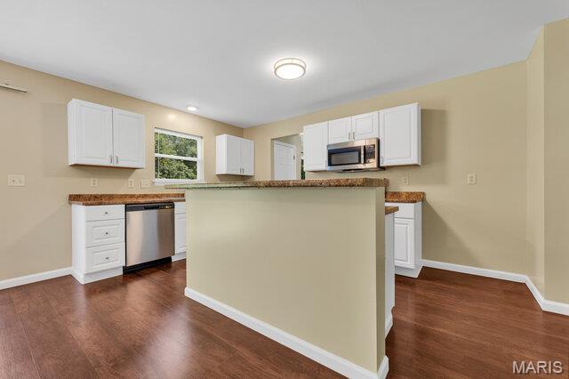 1305 Flintshire Ln, Lake St Louis, MO 63367 - kitchen featuring appliances with stainless steel finishes, white cabinetry, dark wood-style floors, and a center island