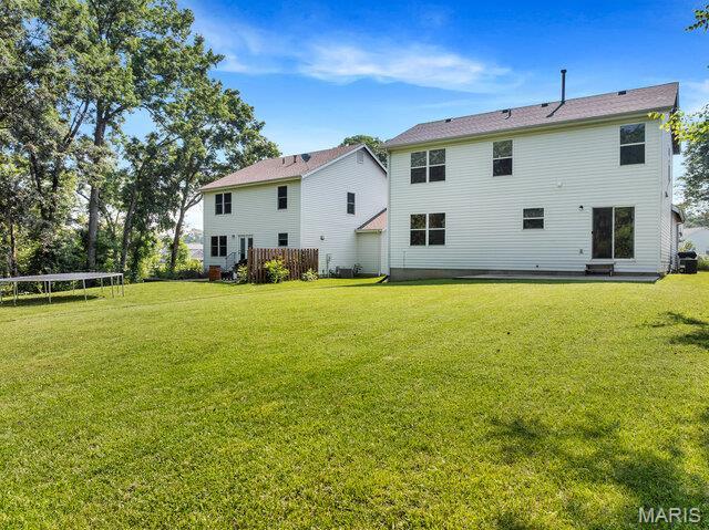1305 Flintshire Ln, Lake St Louis, MO 63367 - rear view of property with a trampoline and a lawn