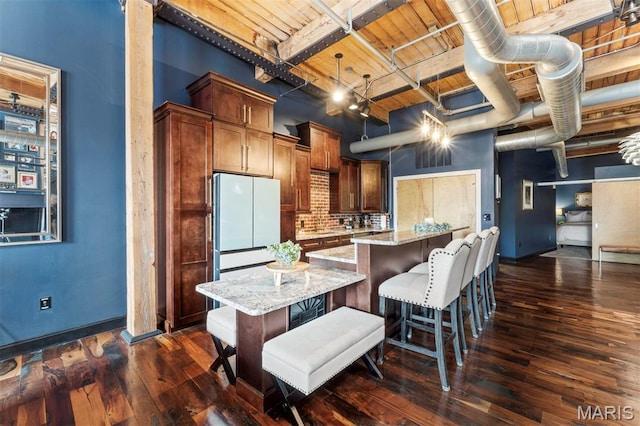 901 Washington Ave Unit 702, Saint Louis, MO 63101 - kitchen with wood ceiling with exposed beams, dark wood-style flooring, light stone counters, a kitchen breakfast bar, and a kitchen island