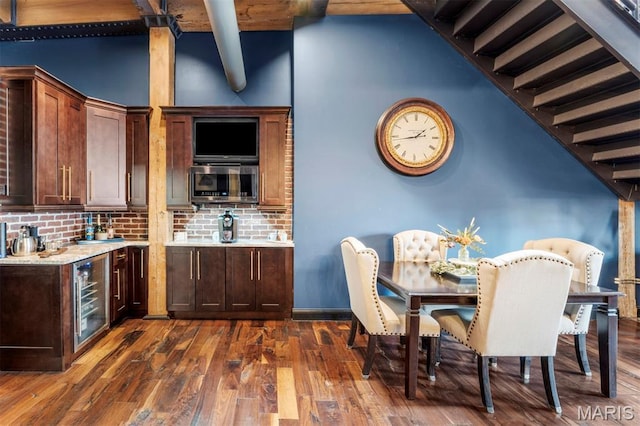 901 Washington Ave Unit 702, Saint Louis, MO 63101 - kitchen featuring wine cooler, decorative backsplash, dark wood-type flooring, stainless steel microwave, and dark brown cabinetry