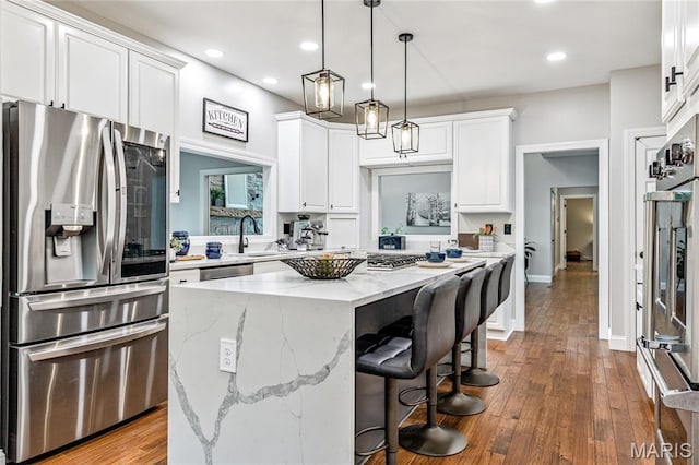 776 Hillenkamp Dr, Weldon Spring, MO 63304 - kitchen with appliances with stainless steel finishes, recessed lighting, a kitchen island, white cabinetry, and hardwood / wood-style flooring