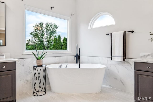776 Hillenkamp Dr, Weldon Spring, MO 63304 - bathroom with vanity, tile walls, a freestanding tub, plenty of natural light, and a wainscoted wall