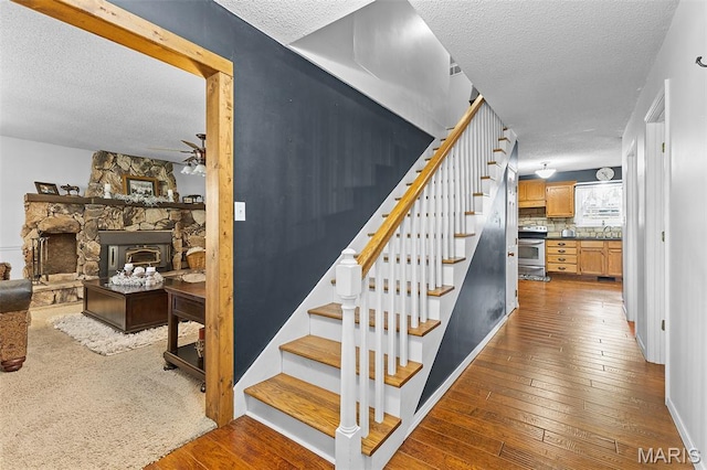 2004 Possum Hollow Rd, Farmington, MO 63640 - stairs featuring a textured ceiling, ceiling fan, hardwood / wood-style flooring, and baseboards