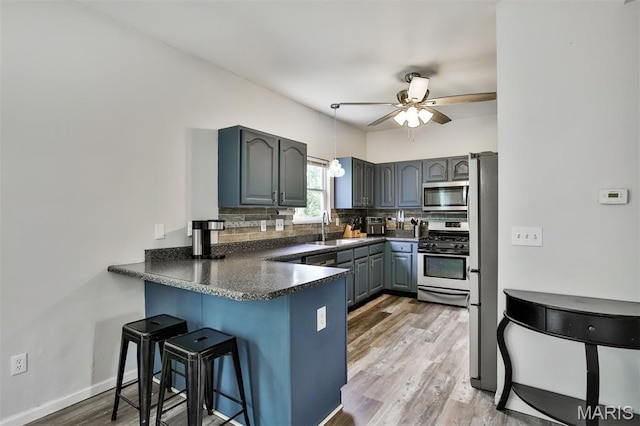505 Lias Way, Wentzville, MO 63385 - kitchen featuring appliances with stainless steel finishes, a peninsula, dark countertops, backsplash, and a breakfast bar area
