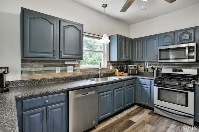 505 Lias Way, Wentzville, MO 63385 - kitchen featuring stainless steel appliances, dark countertops, decorative backsplash, hanging light fixtures, and blue cabinets