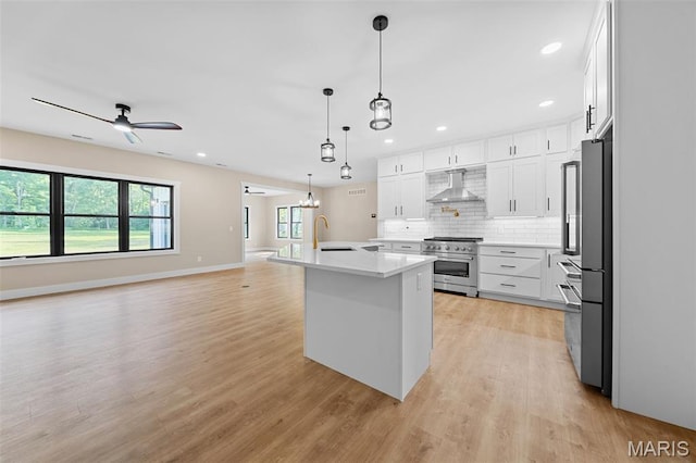 63 Plackemeier Dr, Ofallon, MO 63366 - kitchen featuring high quality appliances, wall chimney exhaust hood, light wood finished floors, tasteful backsplash, and light countertops