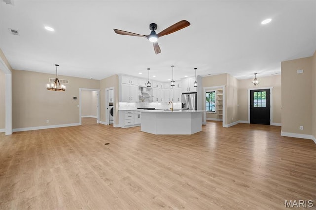 63 Plackemeier Dr, Ofallon, MO 63366 - unfurnished living room featuring a chandelier, a sink, baseboards, washer / clothes dryer, and light wood-style flooring