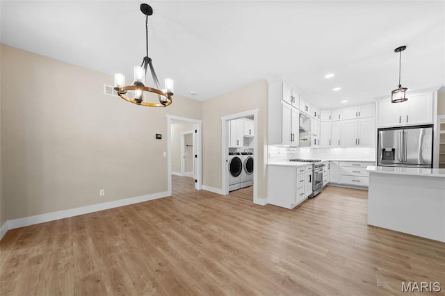 63 Plackemeier Dr, Ofallon, MO 63366 - kitchen with appliances with stainless steel finishes, separate washer and dryer, a chandelier, light countertops, and backsplash