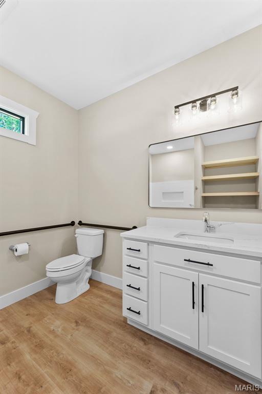 63 Plackemeier Dr, Ofallon, MO 63366 - bathroom with toilet, vanity, baseboards, and wood finished floors