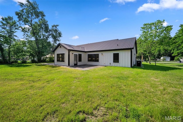 63 Plackemeier Dr, Ofallon, MO 63366 - rear view of house featuring board and batten siding, a patio area, a lawn, central AC, and metal roof
