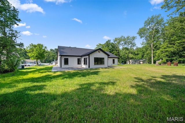 63 Plackemeier Dr, Ofallon, MO 63366 - back of property with a lawn, a patio area, metal roof, and board and batten siding