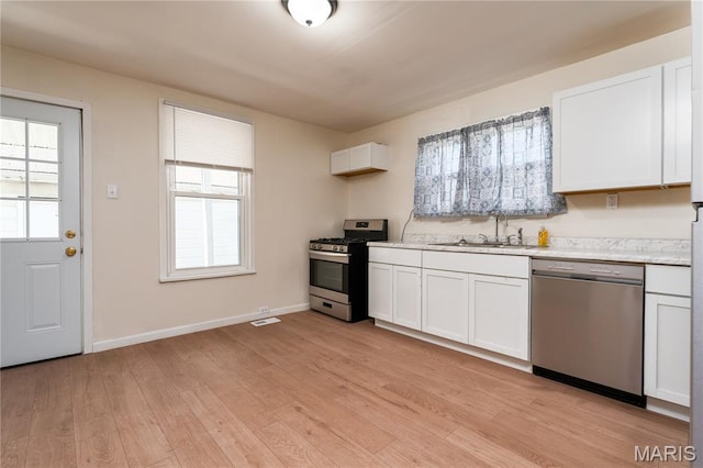 2428 E 25th St, Granite City, IL 62040 - kitchen with stainless steel appliances, a sink, light countertops, light wood-style flooring, and white cabinetry