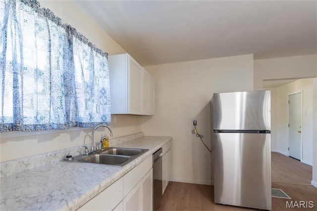 2428 E 25th St, Granite City, IL 62040 - kitchen with appliances with stainless steel finishes, a sink, baseboards, light countertops, and white cabinets