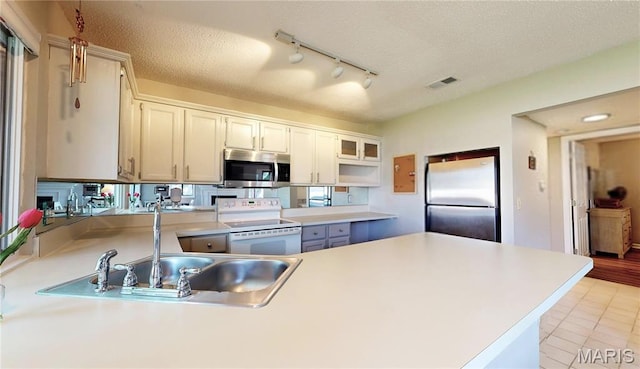 408 Kipling Way Unit A, Weldon Spring, MO 63304 - kitchen with stainless steel appliances, a peninsula, rail lighting, light countertops, and a textured ceiling