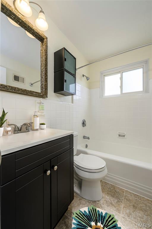 7870 Trenton Ave, University City, MO 63130 - bathroom featuring tile walls, vanity, bathtub / shower combination, and wainscoting
