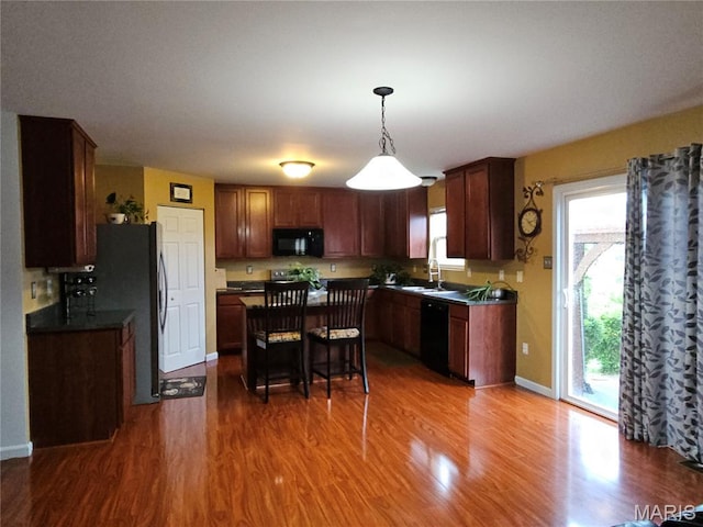1751 Briarmanor Dr, Lake St Louis, MO 63367 - kitchen featuring black appliances, wood finished floors, dark countertops, and decorative light fixtures