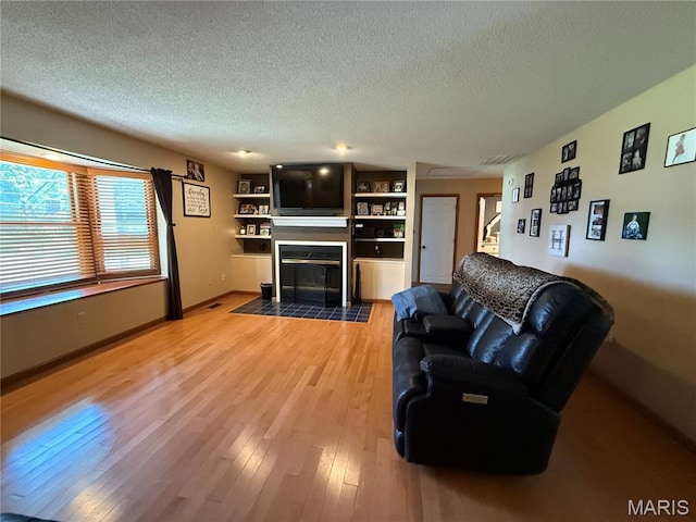506 W Saint Clair St, Freeburg, IL 62243 - living room with a textured ceiling, a fireplace, light wood finished floors, and baseboards