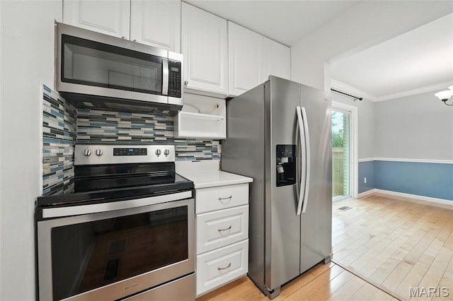 811 Wendevy Ct, Ballwin, MO 63011 - kitchen with stainless steel appliances, backsplash, white cabinetry, light wood-style flooring, and ornamental molding