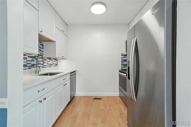 811 Wendevy Ct, Ballwin, MO 63011 - kitchen with appliances with stainless steel finishes, light countertops, tasteful backsplash, white cabinetry, and light wood-style floors