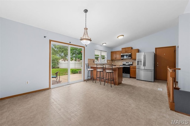1203 Summerwood Dr, Saint Peters, MO 63376 - kitchen with appliances with stainless steel finishes, brown cabinetry, a kitchen bar, tasteful backsplash, and a peninsula