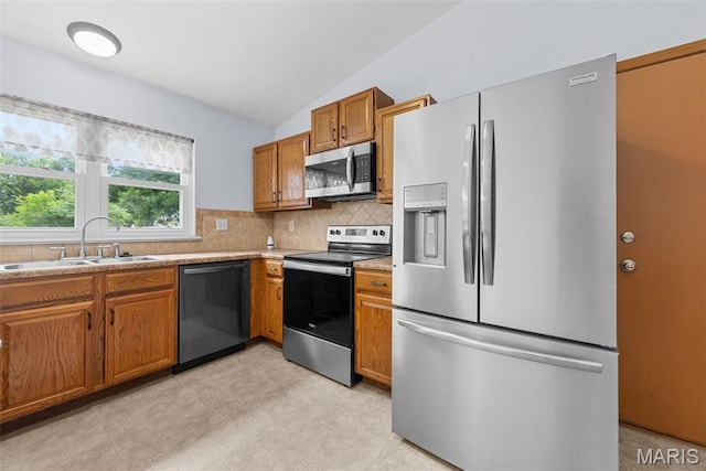 1203 Summerwood Dr, Saint Peters, MO 63376 - kitchen with appliances with stainless steel finishes, brown cabinetry, lofted ceiling, tasteful backsplash, and light countertops