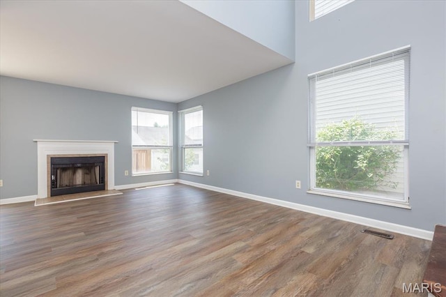 11256 Liberty Landing Dr, Florissant, MO 63033 - unfurnished living room with plenty of natural light, wood finished floors, a fireplace with raised hearth, and baseboards
