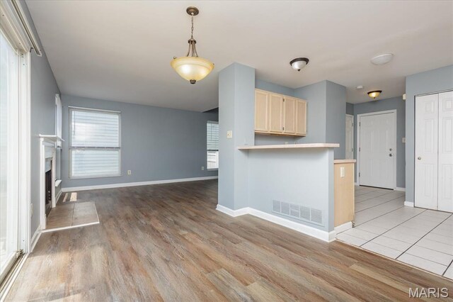 11256 Liberty Landing Dr, Florissant, MO 63033 - kitchen with baseboards, light brown cabinets, light wood finished floors, and a fireplace with raised hearth