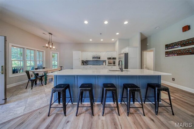 10660 Fawn Rdg, Rolla, MO 65401 - kitchen with a sink, appliances with stainless steel finishes, a chandelier, baseboards, and white cabinets