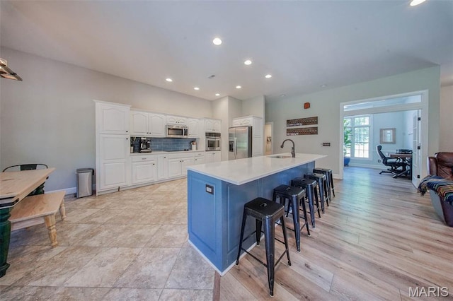 10660 Fawn Rdg, Rolla, MO 65401 - kitchen featuring stainless steel appliances, a sink, white cabinets, a breakfast bar area, and a center island with sink