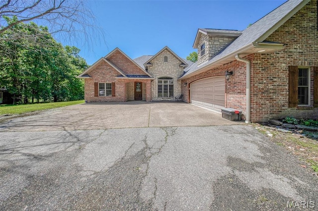 10660 Fawn Rdg, Rolla, MO 65401 - view of front of house with driveway, brick siding, an attached garage, and stone siding