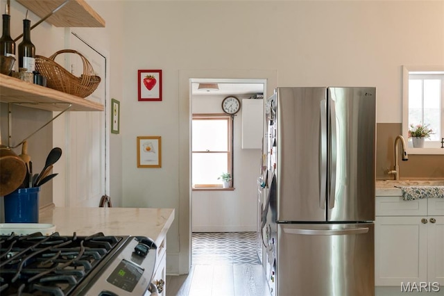 124 W Ross St, Palmyra, MO 63461 - kitchen featuring appliances with stainless steel finishes, a sink, light flooring, open shelves, and light stone countertops