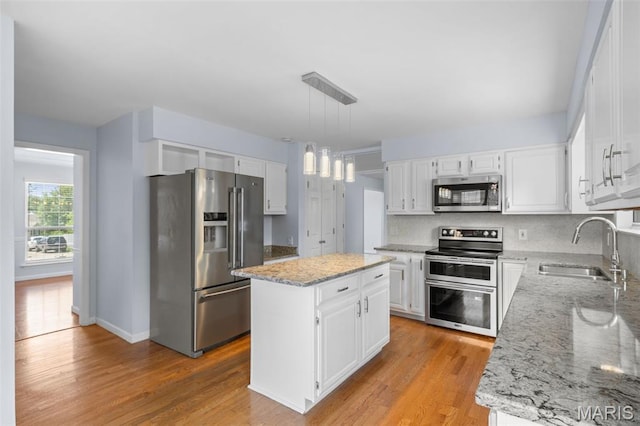 12101 Fahrpark Ln, Saint Louis, MO 63146 - kitchen featuring appliances with stainless steel finishes, a center island, light stone counters, light wood finished floors, and tasteful backsplash