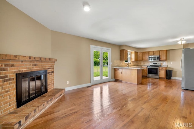 3100 Tally Ho Dr, Saint Charles, MO 63301 - kitchen with appliances with stainless steel finishes, a fireplace, light countertops, open floor plan, and light wood-style floors