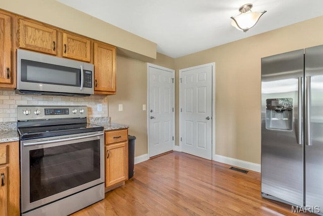 3100 Tally Ho Dr, Saint Charles, MO 63301 - kitchen featuring stainless steel appliances, light wood-style floors, and decorative backsplash