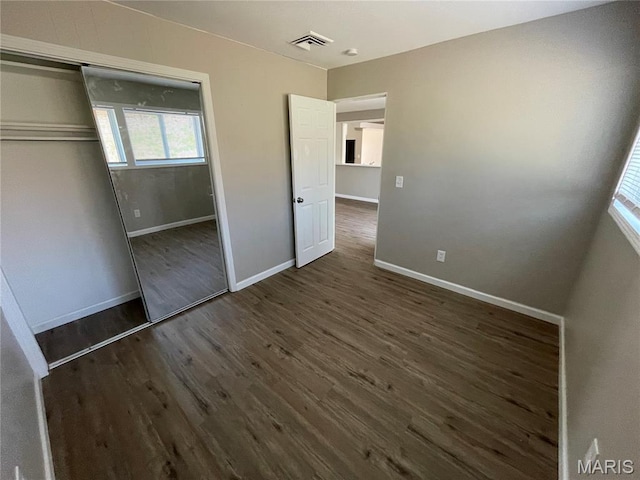 415 Waterford Dr, Florissant, MO 63033 - unfurnished bedroom featuring multiple windows, dark wood-type flooring, and a closet