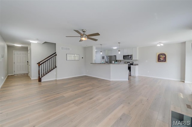 3325 Charlestowne Crossing Dr, Saint Charles, MO 63301 - unfurnished living room with ceiling fan, light wood-style floors, and stairway