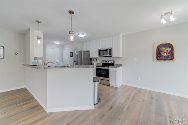 3325 Charlestowne Crossing Dr, Saint Charles, MO 63301 - kitchen with stainless steel appliances, light wood finished floors, white cabinets, a peninsula, and hanging light fixtures